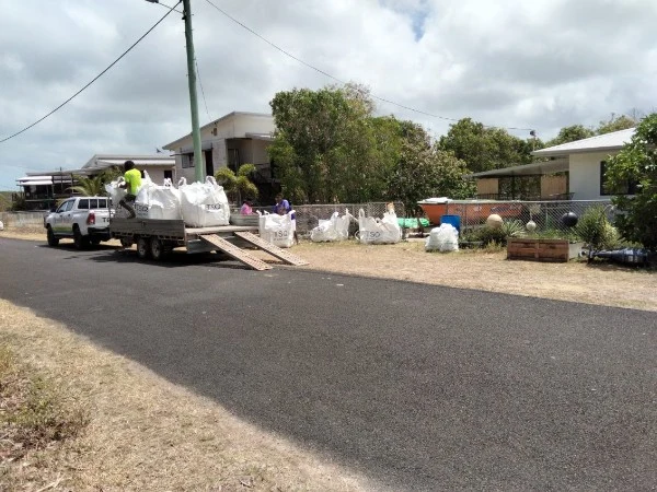 Collection bags beside a roadside loading ramp and trailer.