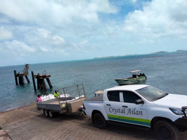 Crystal Ailan ute and loaded trailer at a boat ramp, with the collection boat offshore.